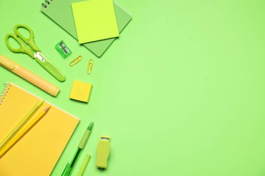 Yeşil arka planda farklı kırtasiye malzemesi, düz. Metin için boşluk