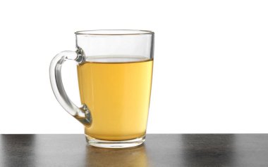 Yeşil çayı fincanda beyaz arka planda gri desenli masada tazeliyor.