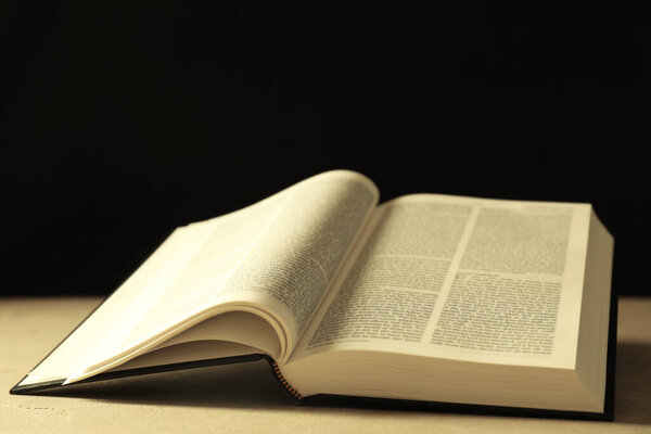 Открытая Библия на английском языке на бежевом столе