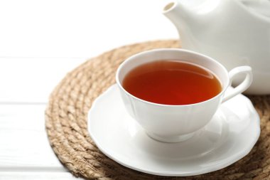 Aromatik siyah çay fincanda ve çaydanlık beyaz ahşap masada, yakın plan