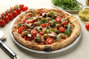 Mantarlı, zeytinli, domatesli ve beyaz desenli masanda kesilmiş lezzetli bir pizza.