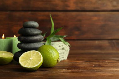 Taze limonlu spa kompozisyonu, çakıl taşları ve ahşap masada yanan mumlar, yakın çekim. Metin için boşluk