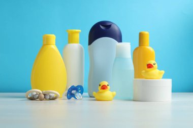 Bebek kozmetik ürünleri, emzik ve lastik ördekler açık mavi arka planda gri masada