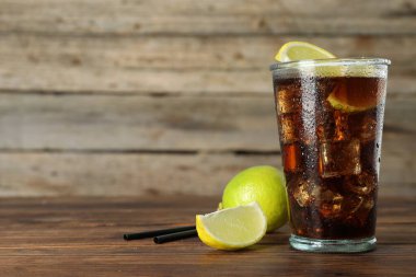 Limon dilimli buzlu kola ve ahşap masada limon, yakın plan. Metin için boşluk