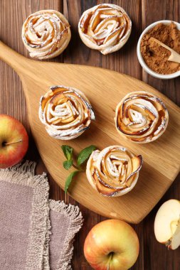 Ahşap masada servis edilen pudra şekerli lezzetli elma gülleri.