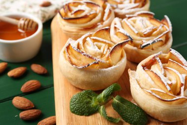 Yeşil ahşap masada servis edilen pudra şekerli elma gülleri, yakın plan.