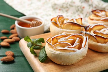 Yeşil ahşap masada servis edilen pudra şekerli elma gülleri, yakın plan.