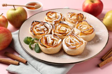 Pembe ahşap masada servis edilen pudra şekerli elma gülleri, yakın plan.