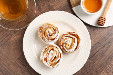 Taze pişmiş elma gülleri, bal ve çay ahşap masada, düz uzanmış.