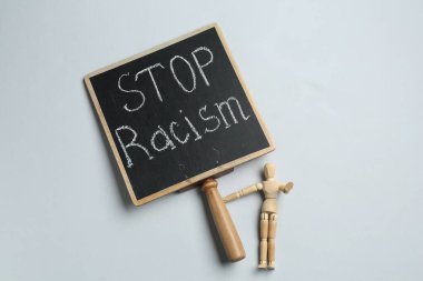 Chalkboard with phrase Stop Racism and human figure on light grey background, top view clipart