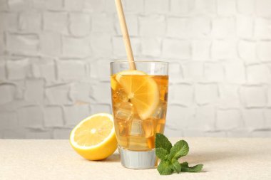 Buzlu çayı saman, nane ve limon dilimleri ile tazeleyerek açık dokulu masada gri arka planda, yakın plan