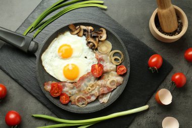 Gri masada servis edilen lezzetli kızarmış yumurta, pastırma ve mantar.