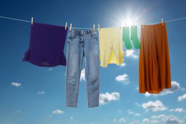 Different clothes drying on washing line against blue sky