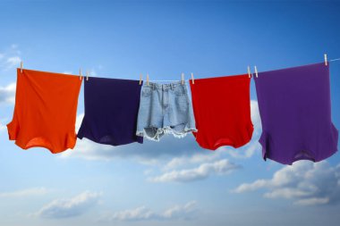 Different clothes drying on washing line against blue sky