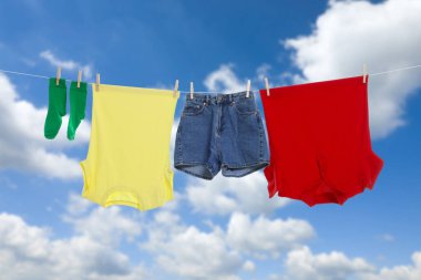 Different clothes drying on washing line against blue sky