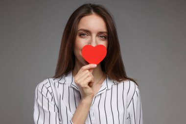 Sevgililer Günün kutlu olsun. Gri arka planda kağıt kalpli güzel bir kadın.