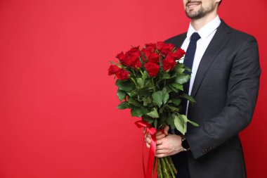 Sevgililer Günün kutlu olsun. Kırmızı arka planda gül buketi olan adam, yakın plan. Metin için boşluk