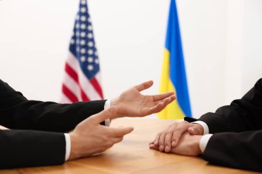 Diplomats negotiating during meeting at wooden table indoors, closeup clipart