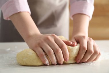 Beyaz masada tarçınlı ekmek için hamur yoğuran kadın, yakın plan.