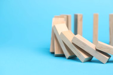 Domino etkisi. Tahta bloklar açık mavi arka plana düşüyor, yakın plan. Metin için boşluk