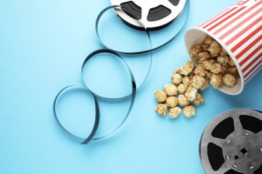 Tatlı patlamış mısır ve film makaraları açık mavi arka planda, düz uzanmış