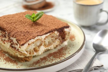 Beyaz masadaki lezzetli tiramisu parçası, yakın plan.