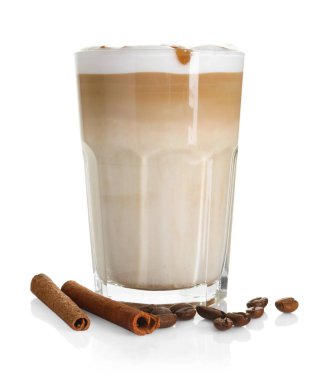 Bardakta latte macchiato, beyaz kahve çekirdekleri ve tarçın.