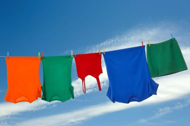 Different clothes drying on washing line against blue sky