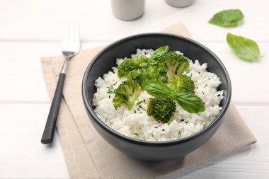 Brokolili lezzetli pirinç ve beyaz ahşap masada fesleğen, yakın plan.