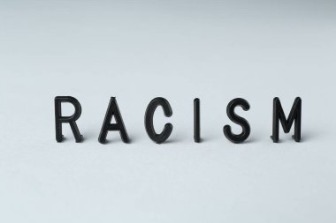 Word Racism on light grey background, closeup clipart