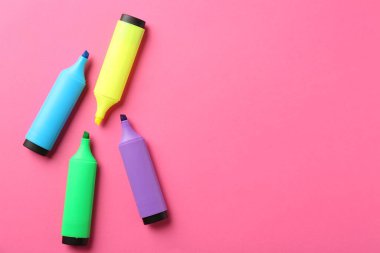Pembe arka planda parlak fosforlu kalemler, düz yatış. Metin için boşluk