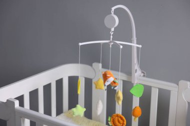 Çocuk odasındaki gri duvarın yanında şirin bebek arabası olan bir beşik.