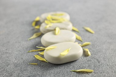 Gri masadaki kaplıca taşları ve taç yaprakları, yakın plan.