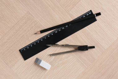 Cetvel, kalem, silgi ve pusula tahta masada, düz yerde.