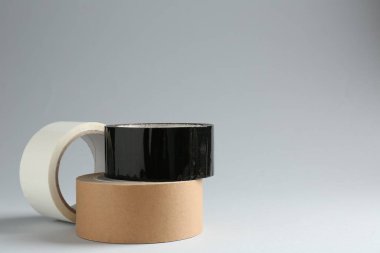 Gri arkaplanda farklı yapıştırıcı bantların ruloları, metin için boşluk