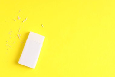 Sarı arka planda bir silgi ve kırıntılar, üst manzara. Metin için boşluk