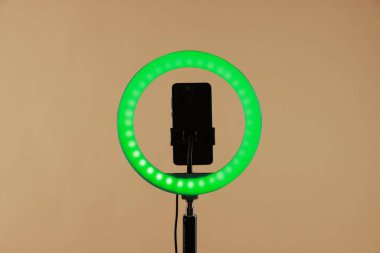 Bej arka planda akıllı telefon ile halka lambası