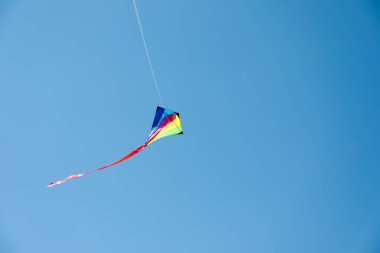 Mavi gökyüzünde uçan renkli bir uçurtma