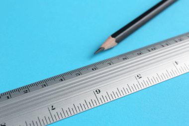 Açık mavi arka planda cetvel ve kalem, yakın plan. Metin için boşluk