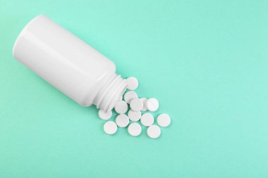 Turkuaz arka planda bir şişe antibiyotik hapı. Metin için boşluk