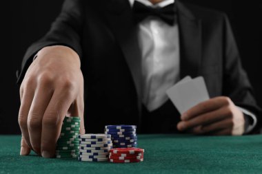 Kumar masasında poker oynayan kart ve kumarhane fişleri olan adam, yakın plan.