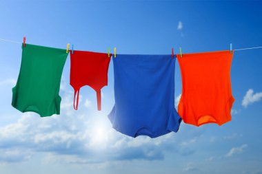 Different clothes drying on washing line against blue sky