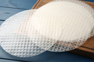 Mavi ahşap masadaki yenilebilir pirinç kağıtları, yakın plan.