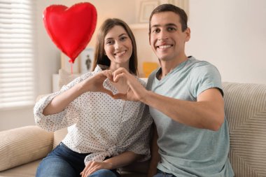 Lovely couple making heart with hands indoors. Valentine's day celebration