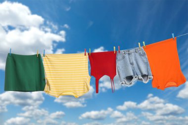 Different clothes drying on washing line against blue sky
