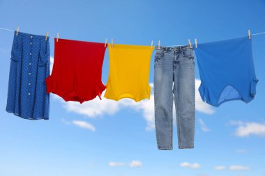 Different clothes drying on washing line against blue sky