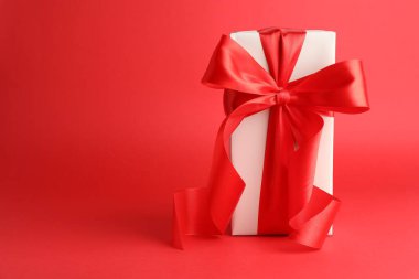 Kırmızı zemin üzerinde güzel bir fiyonk olan hediye kutusu, metin için boşluk