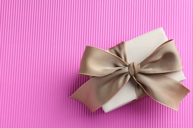 Pembe arka planda güzel bir fiyonklu hediye kutusu, üst manzara. Metin için boşluk