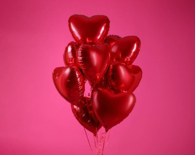 Pembe arka planda kalp şeklinde kırmızı balonlar. Sevgililer Günü