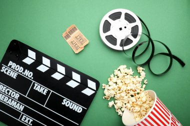 Film alkışı, lezzetli patlamış mısır, biletler ve yeşil arka planda film makarası, düz konum
